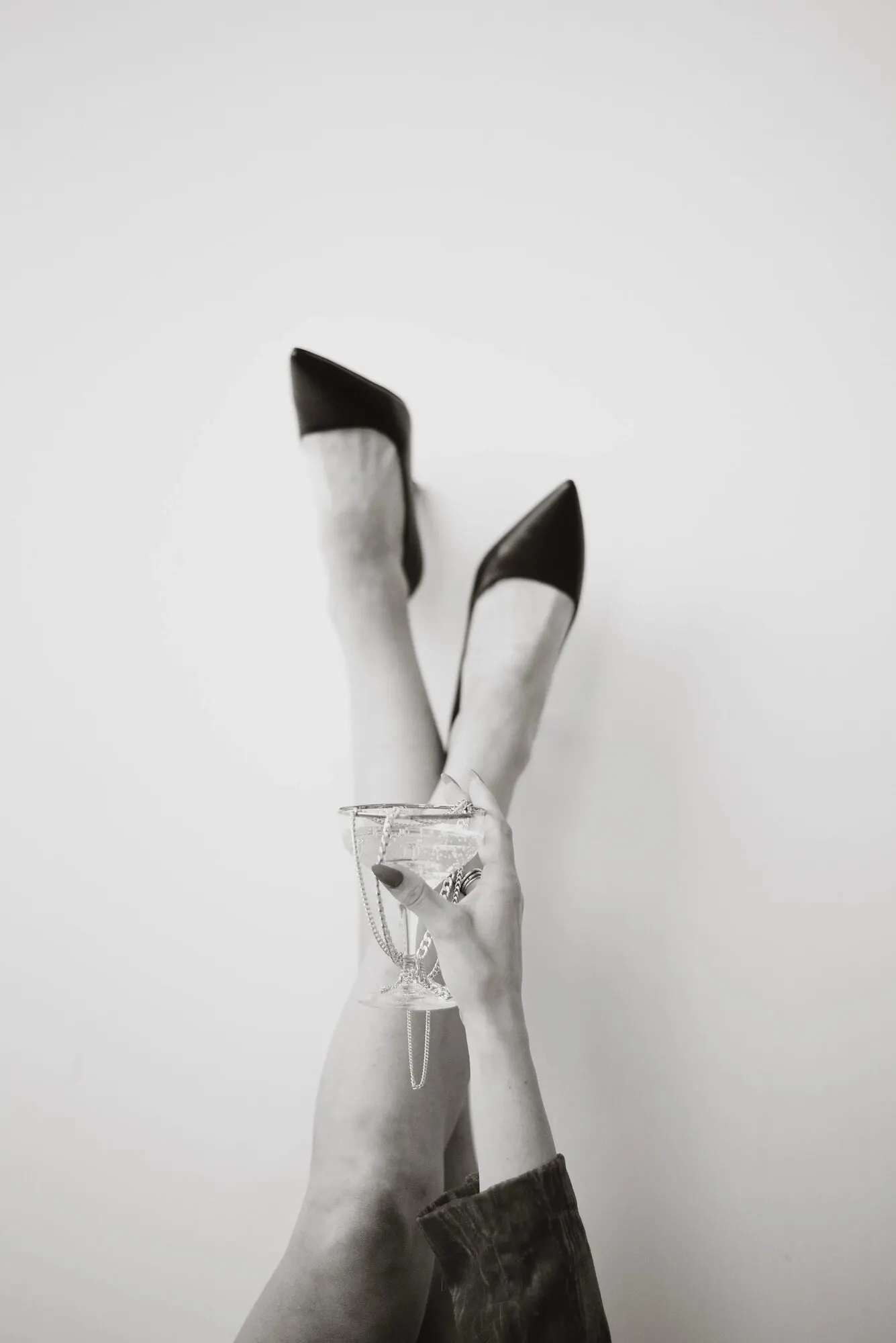 Legs raised against a pale wall, a champagne coupe balanced above.