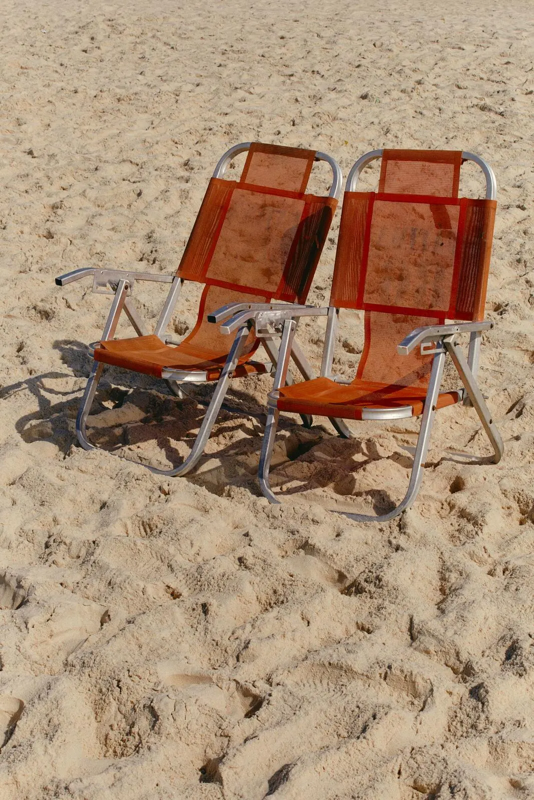 Two empty chairs on sand.