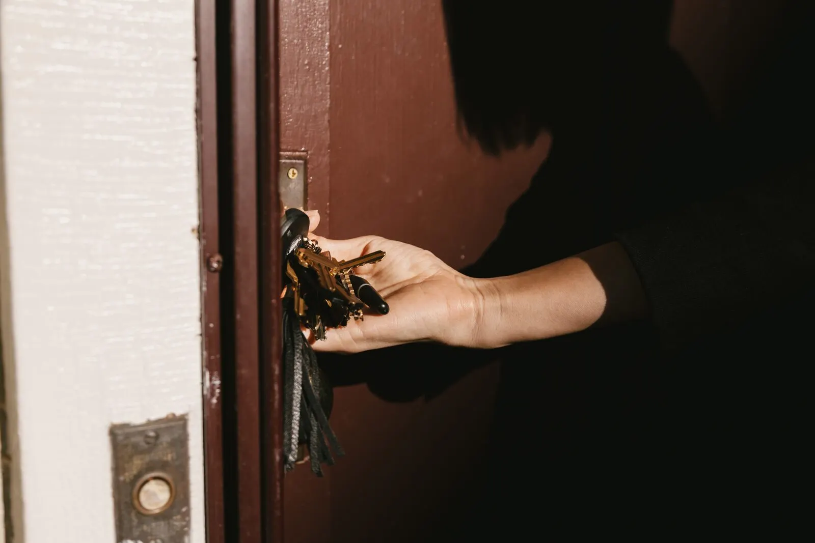 A hand holding keys at a door — access, threshold, entry.