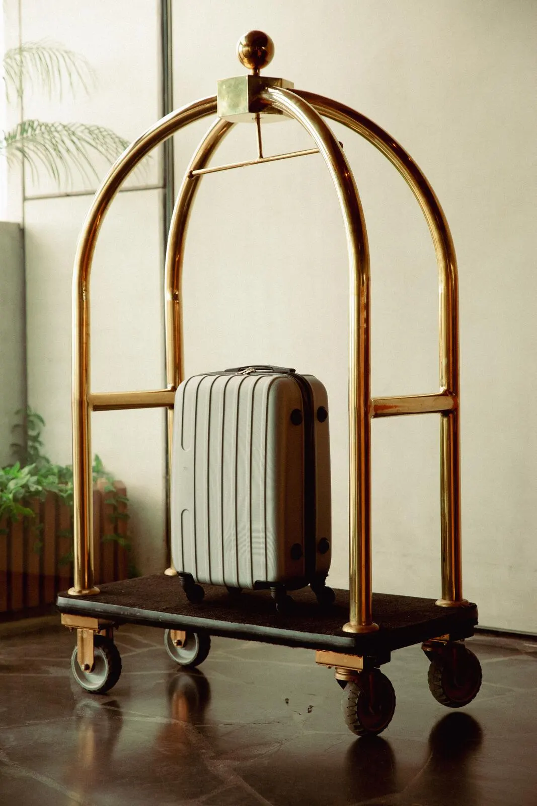 A brass hotel luggage cart standing loaded in a lobby.