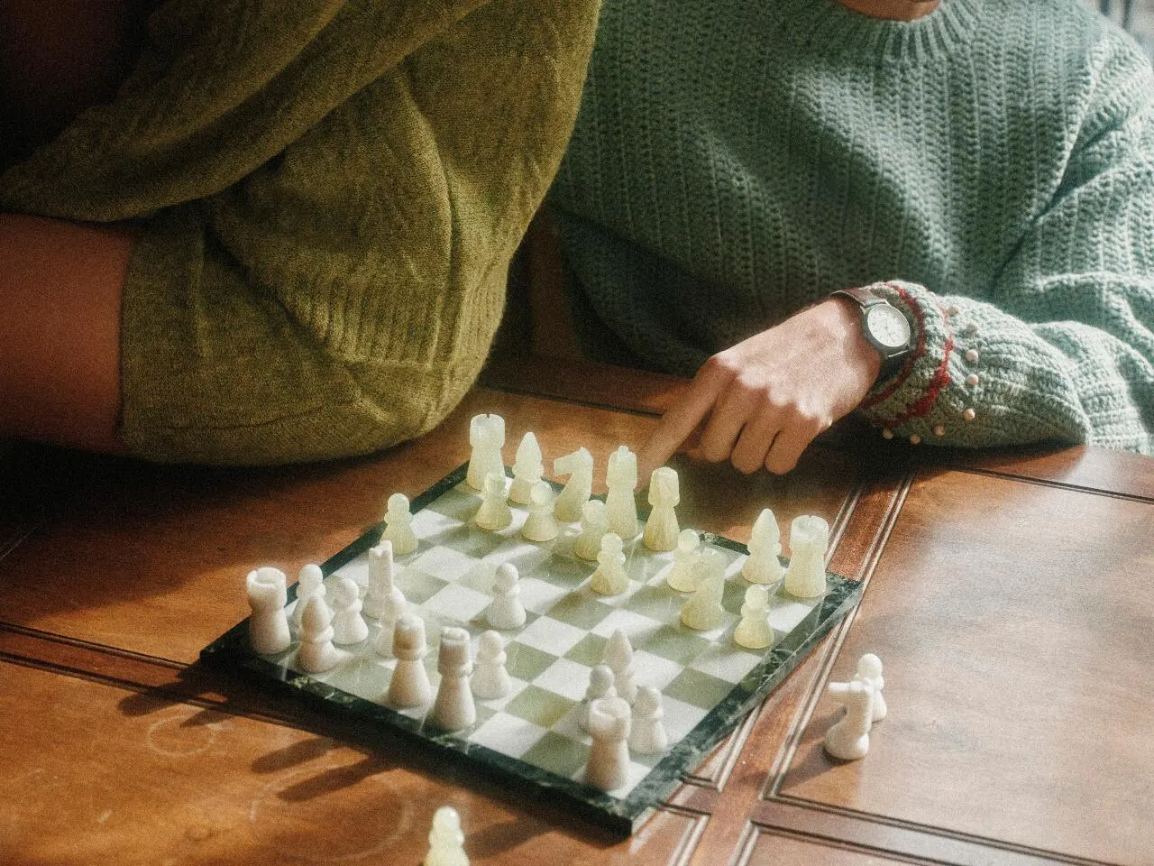 Hands over a chess board mid-game, wide frame.
