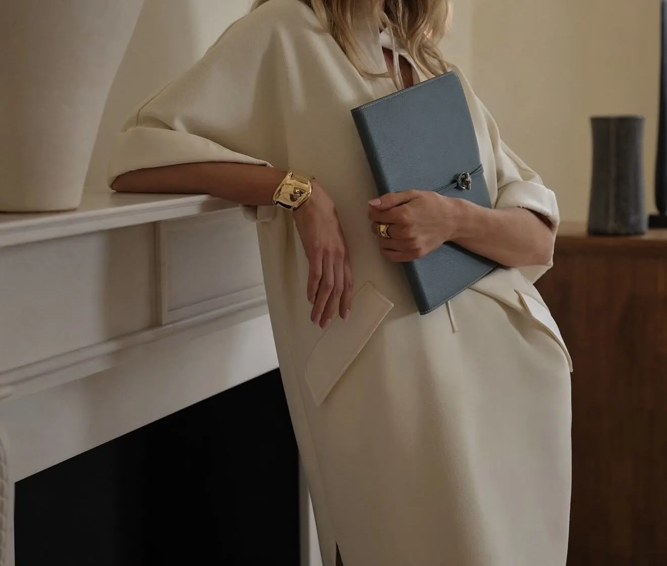 Cream tailoring, a leather portfolio and a gold watch.