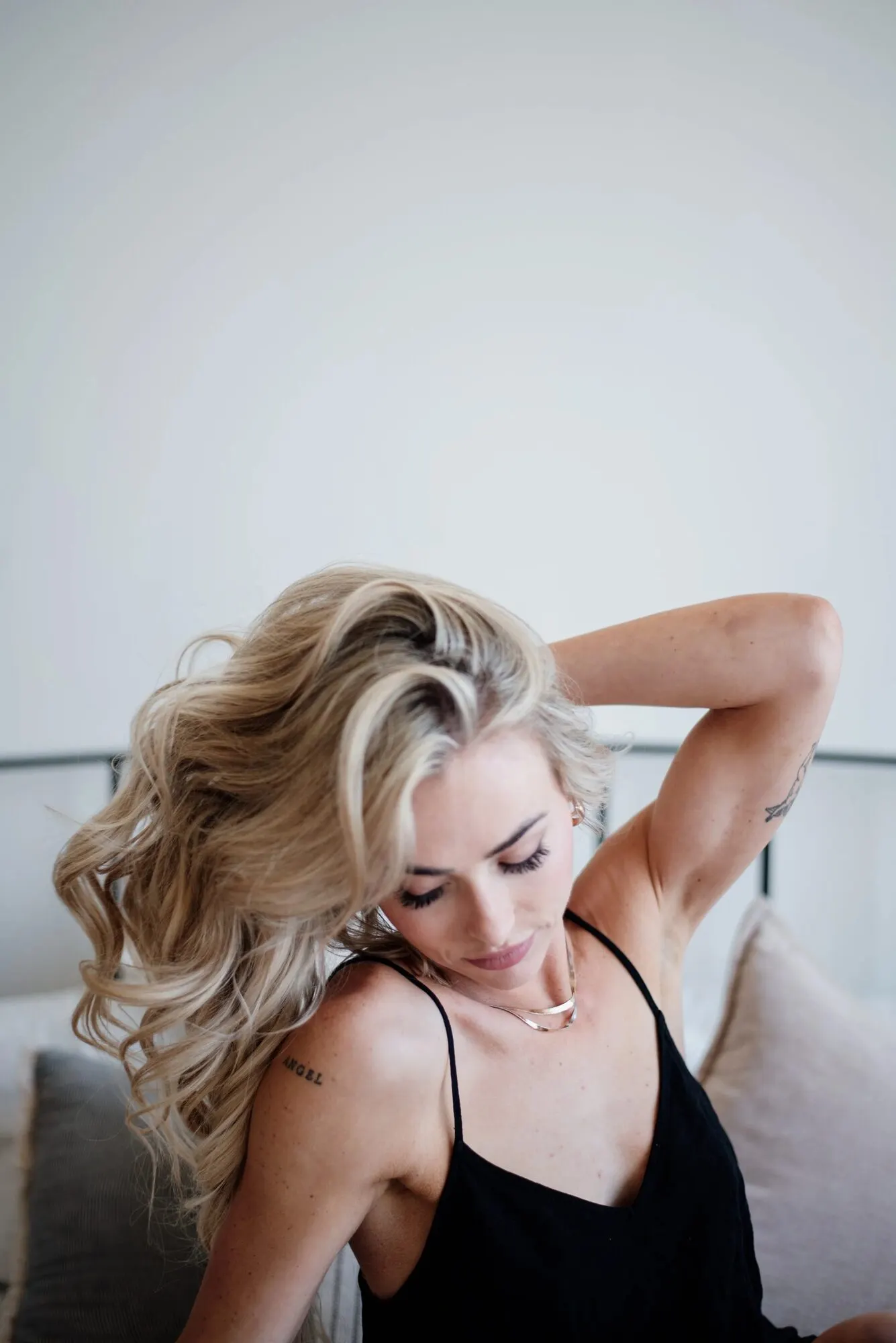 Figure in a black slip turned away, long hair falling across the back, dim room.