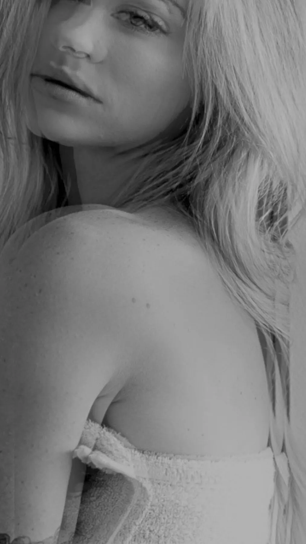 A close black and white crop of Tyler Tanner — bare shoulder, hair, the side of her face.