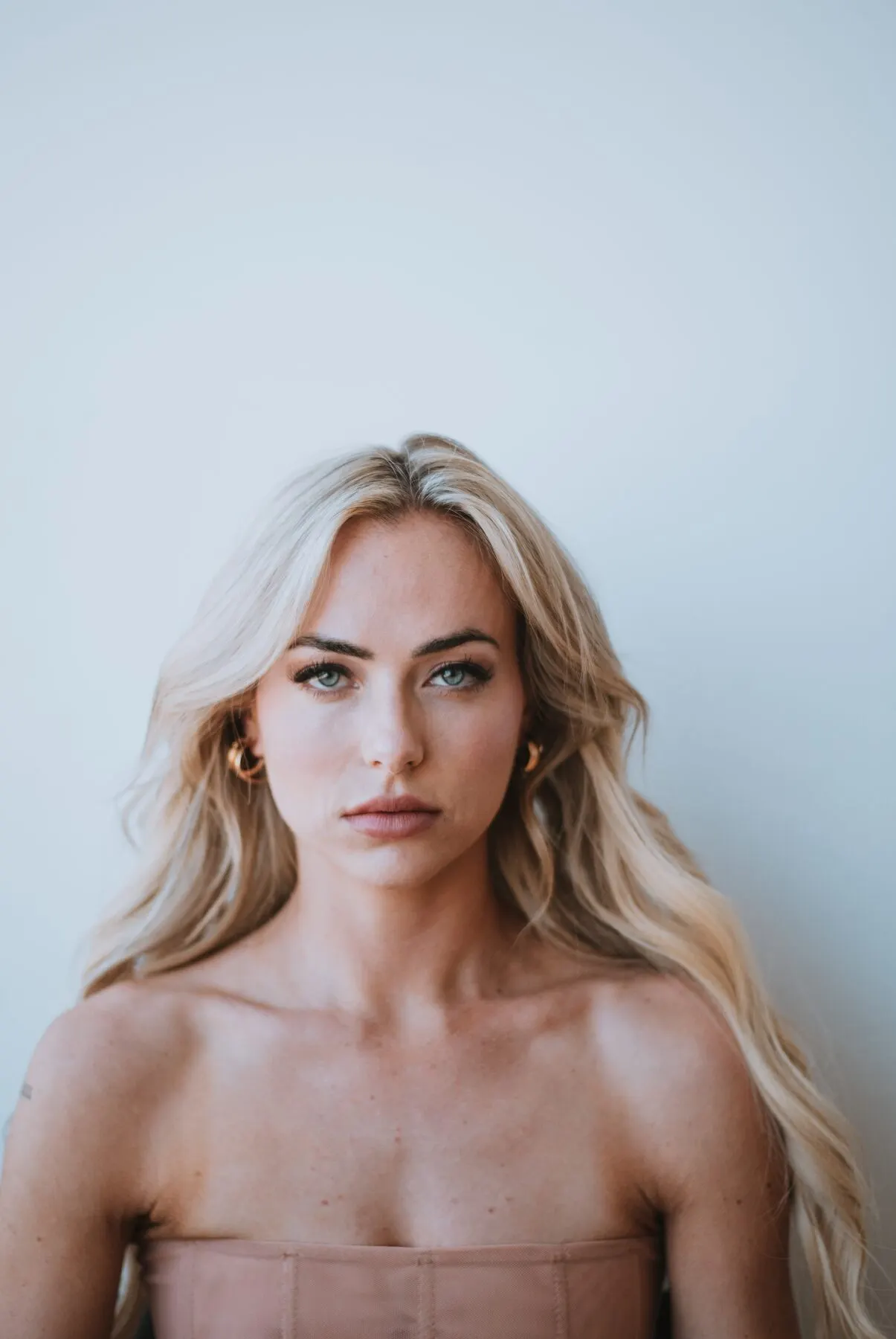Tyler Tanner photographed straight to camera against a pale wall, unsmiling, hair back.