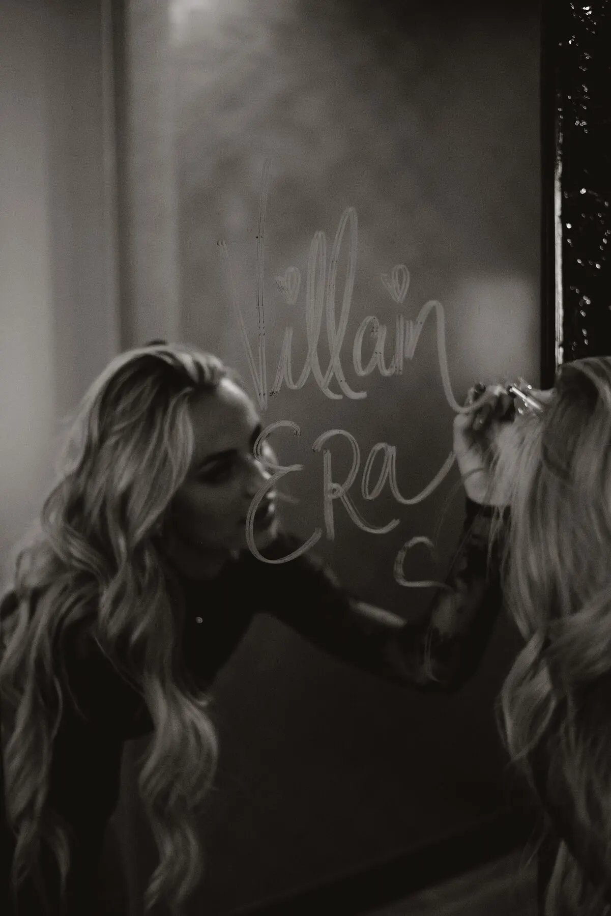 Black and white — Tyler Tanner in a mirror with 'Villain Era' written across the glass.